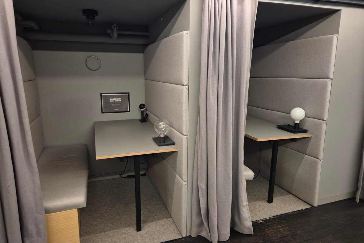 Cabinas con mesa y cortina para hacer llamadas en un espacio de coworking